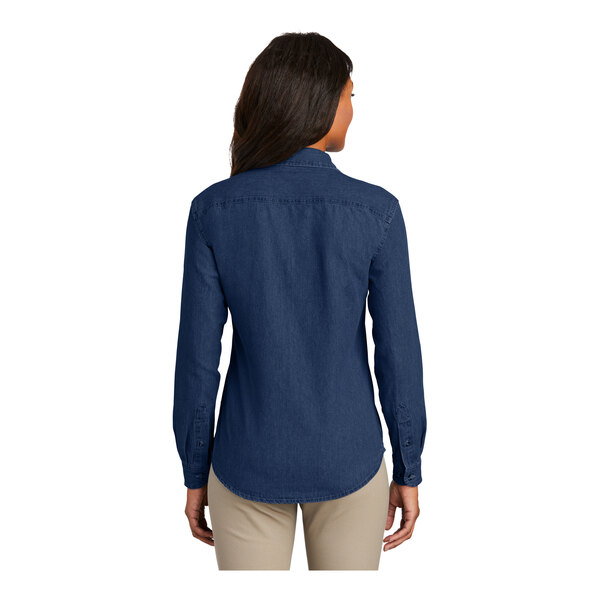 A woman wearing an ink blue Port & Company short sleeve denim button-down shirt.