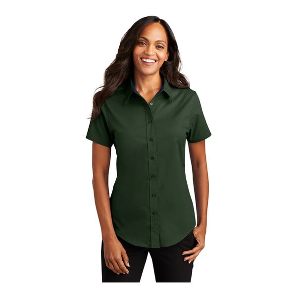 A woman wearing a dark green and navy Port Authority short sleeve button down dress shirt.