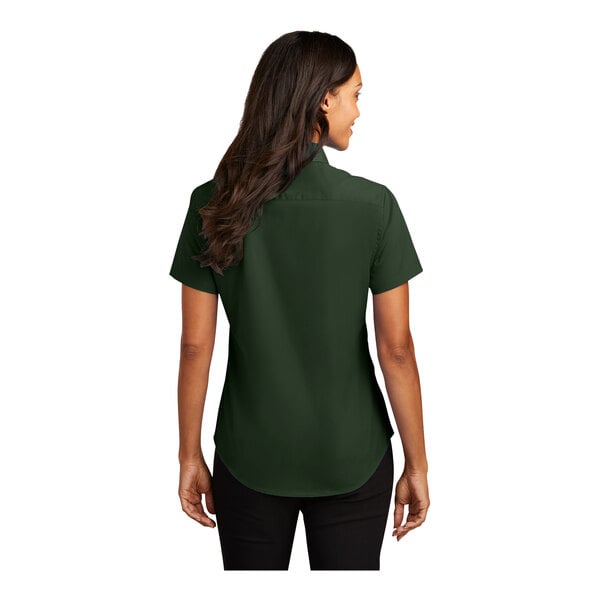 A woman wearing a dark green Port Authority short sleeve dress shirt.