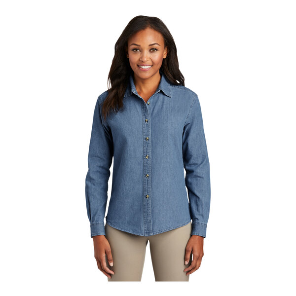 A woman wearing a Port & Company faded blue short sleeve denim button-down shirt.