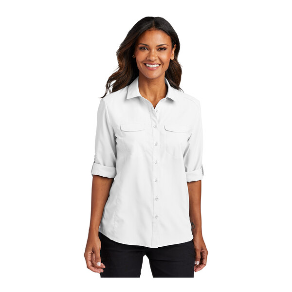 A woman wearing a white short sleeve Port Authority shirt.