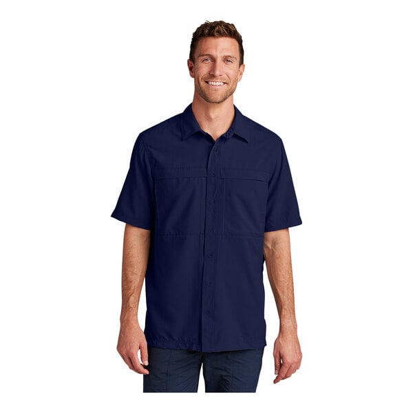 A man wearing a Port Authority navy short sleeve moisture wicking shirt.