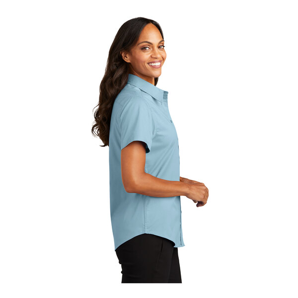 A woman wearing a Port Authority light blue short sleeve dress shirt.