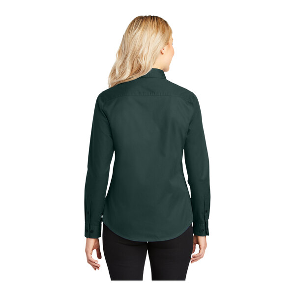 A woman wearing a dark green Port Authority long sleeve dress shirt.