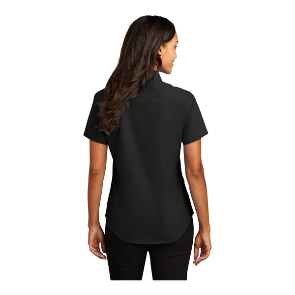 A woman wearing a black Port Authority short sleeve dress shirt with a black and light stone collar.