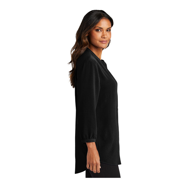 A woman wearing a black Port Authority short sleeve blouse.