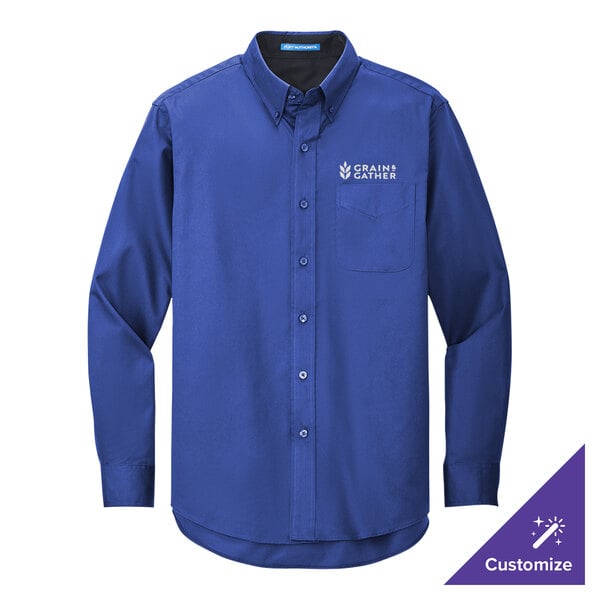A medium blue Port Authority long sleeve dress shirt on a counter with a logo on the chest.