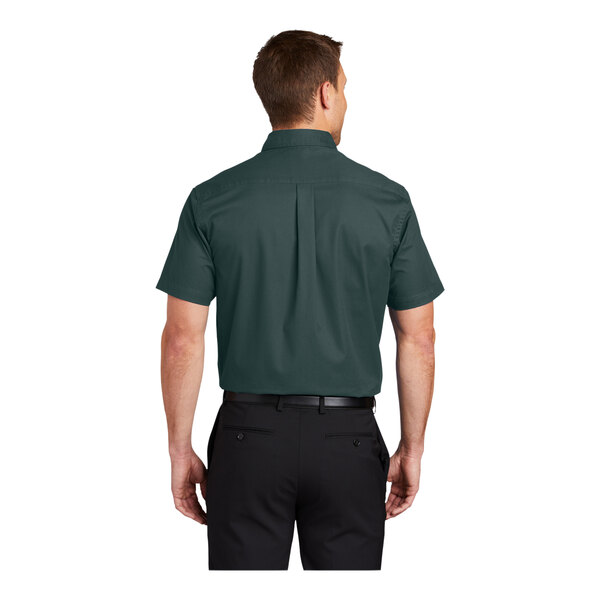 A man wearing a Port Authority dark green short sleeve dress shirt.
