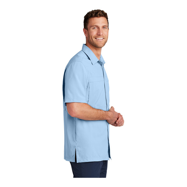 A man wearing a light blue Port Authority short sleeve performance shirt.