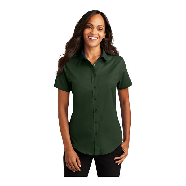 A woman wearing a dark green Port Authority short sleeve button down dress shirt.