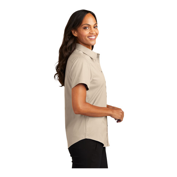 A woman smiling in a tan Port Authority short sleeve dress shirt.