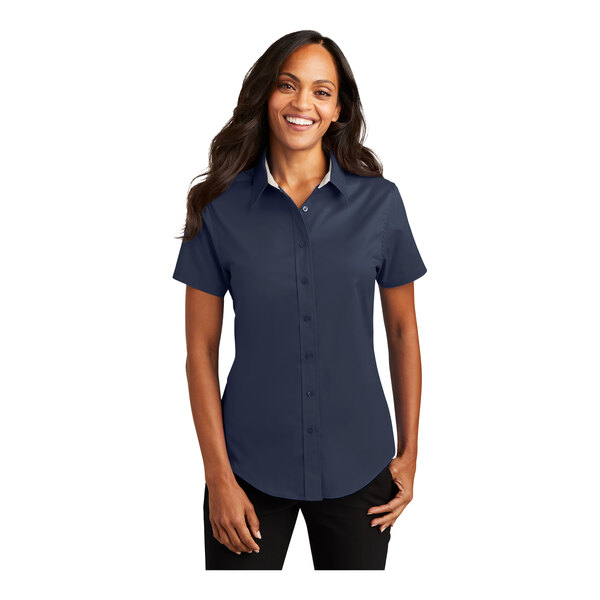 A woman wearing a Port Authority navy and light stone short sleeve button down dress shirt.