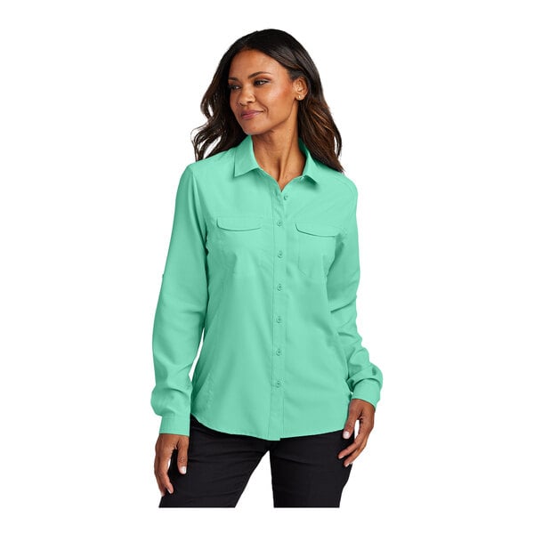 A woman wearing a bright seafoam green Port Authority short sleeve shirt.