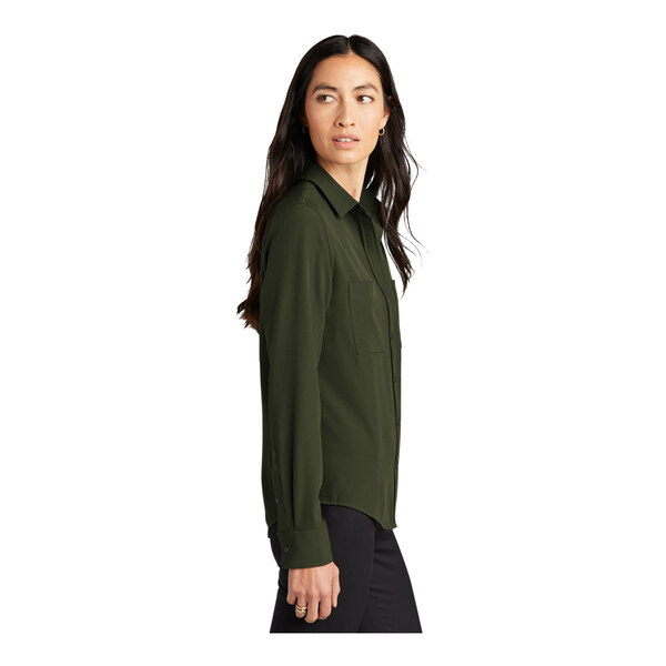A woman wearing a Mercer+Mettle long sleeve green camp blouse with the sleeves rolled up.