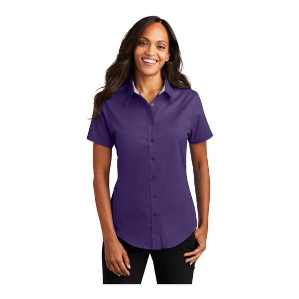 A woman wearing a purple and light stone Port Authority short sleeve button down dress shirt.