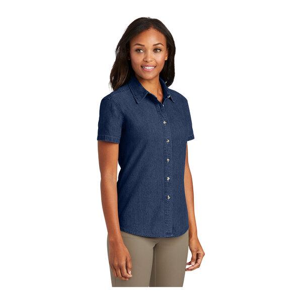 A woman wearing a Port & Company ink blue short sleeve denim button-down shirt.