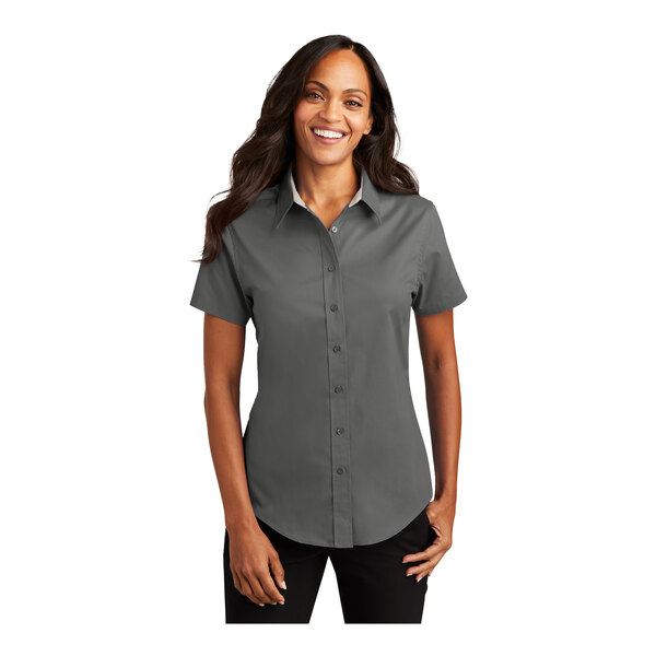 A woman wearing a Port Authority steel gray and light stone short sleeve button down shirt.