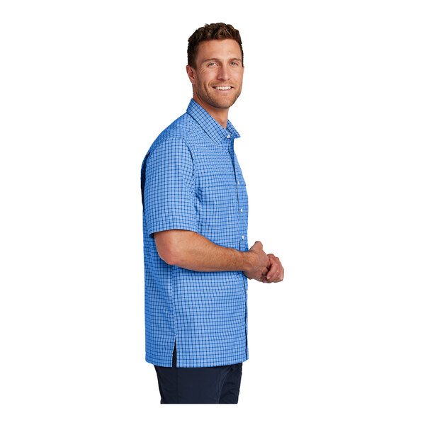 A man wearing a blue and white mini plaid short sleeve shirt.
