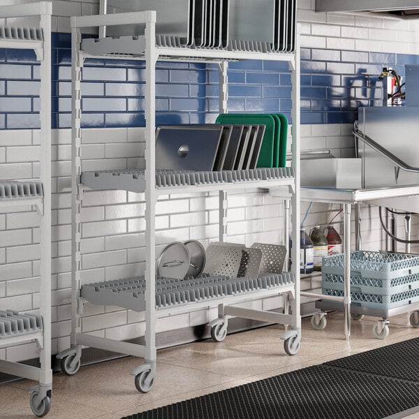 A Cambro Camshelving Premium drying rack cart with trays on white and blue shelves.