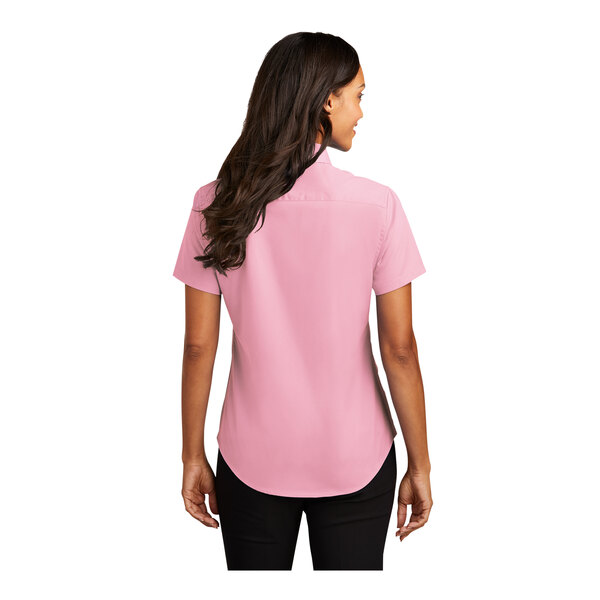 A woman wearing a light pink Port Authority short sleeve dress shirt.