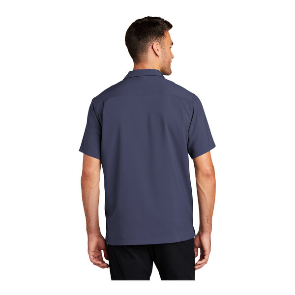 A man wearing a Port Authority short sleeve staff shirt in blue.