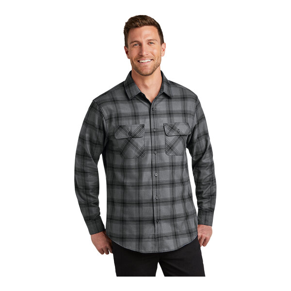 A man wearing a Port Authority gray and black plaid long sleeve flannel shirt.