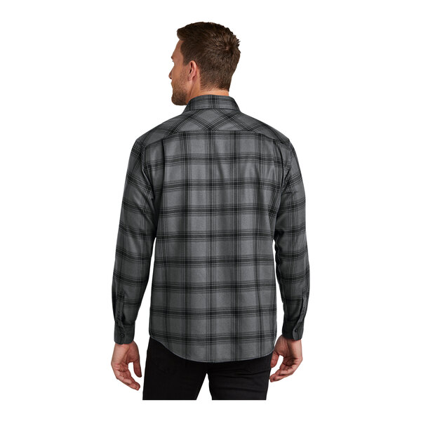 A man wearing a gray and black Port Authority plaid flannel shirt.