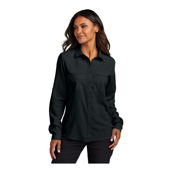 A woman wearing a black Port Authority short sleeve button-down shirt.