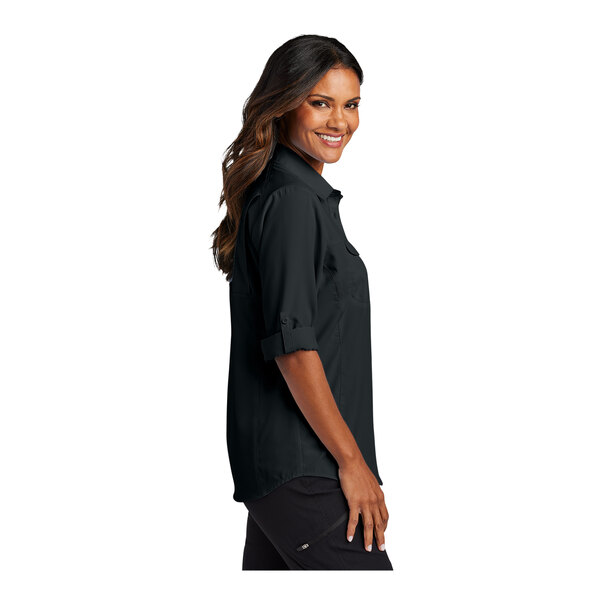 A woman wearing a black Port Authority short sleeve shirt.