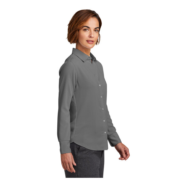 A woman wearing a shadow gray long sleeve Brooks Brothers button down blouse.