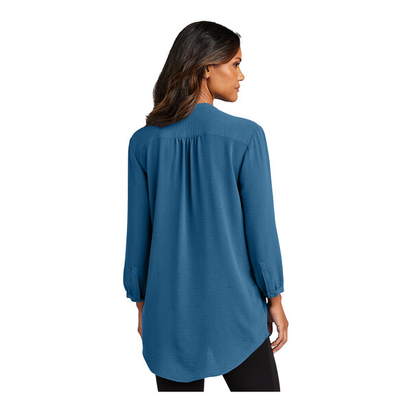 A woman wearing a blue short sleeve blouse with a tunic style.