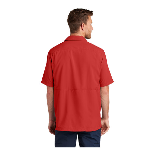 A man wearing a Port Authority short sleeve red shirt.