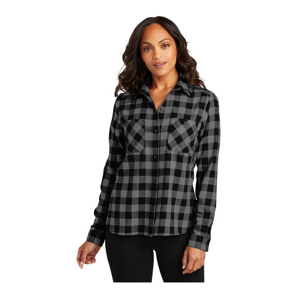 A woman wearing a gray and black buffalo check Port Authority flannel shirt.