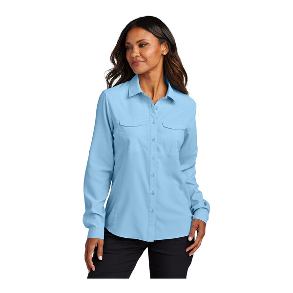 A woman wearing a light blue Port Authority short sleeve button-down shirt.
