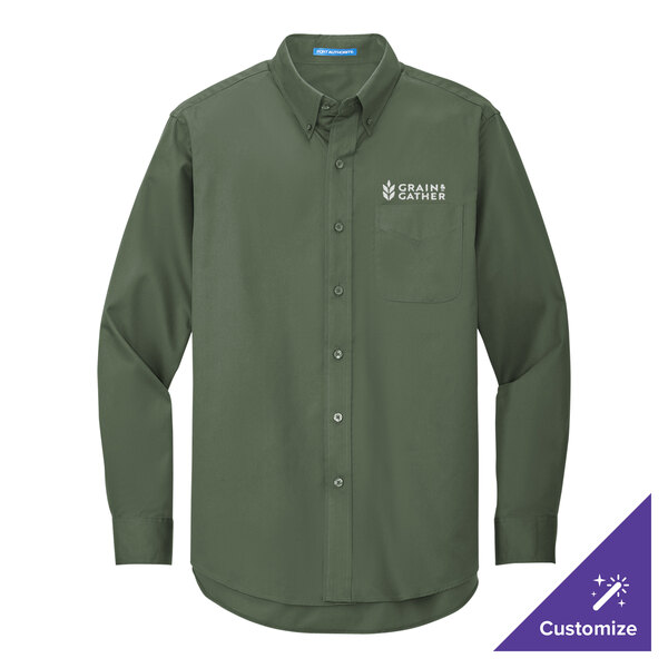 A Port Authority long sleeved green dress shirt on a counter with the company logo.