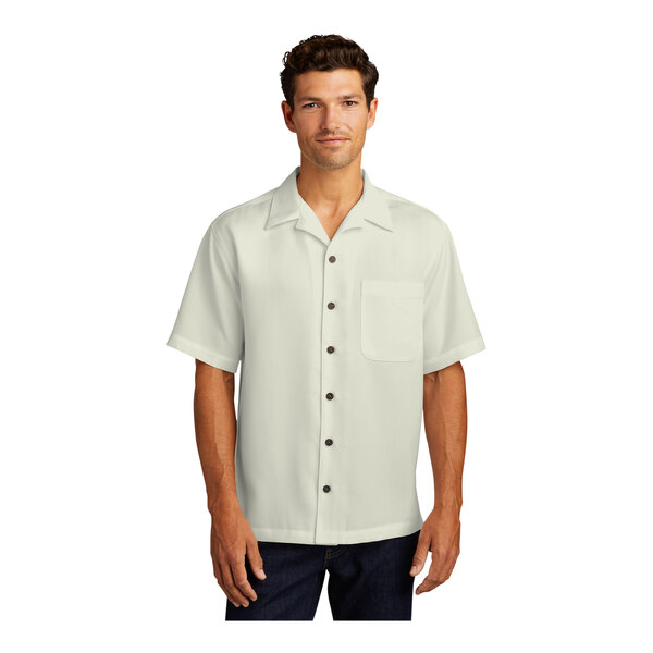 A man wearing a Port Authority ivory short sleeve camp shirt with buttons.