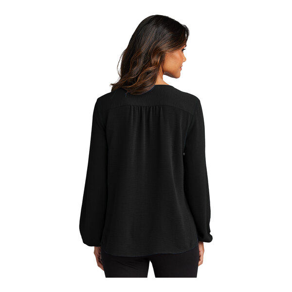 A woman wearing a black short sleeve blouse with a deep black color.