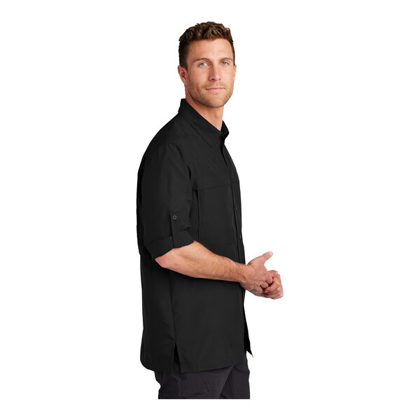 A man wearing a black Port Authority long sleeve stretch poplin shirt.