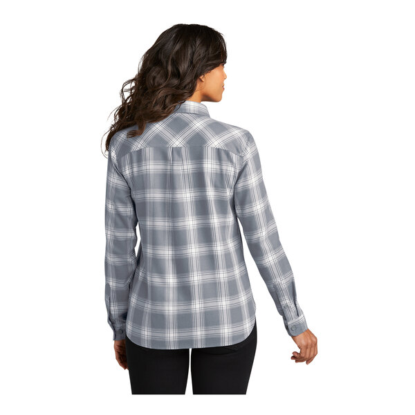 A woman wearing a gray and white plaid flannel shirt.