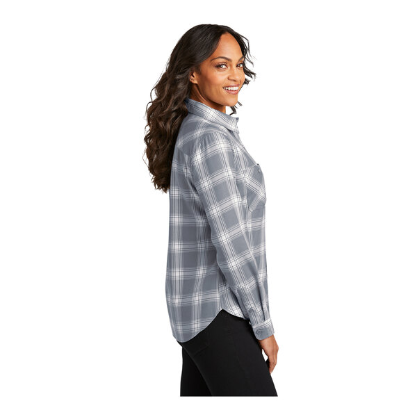 A woman with long brown hair from the back wearing a gray and cream plaid flannel shirt.