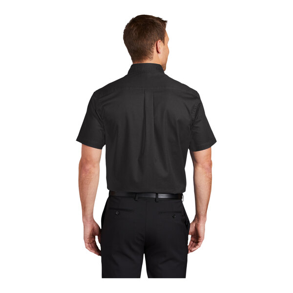 A man wearing a black and light stone Port Authority short sleeve dress shirt.