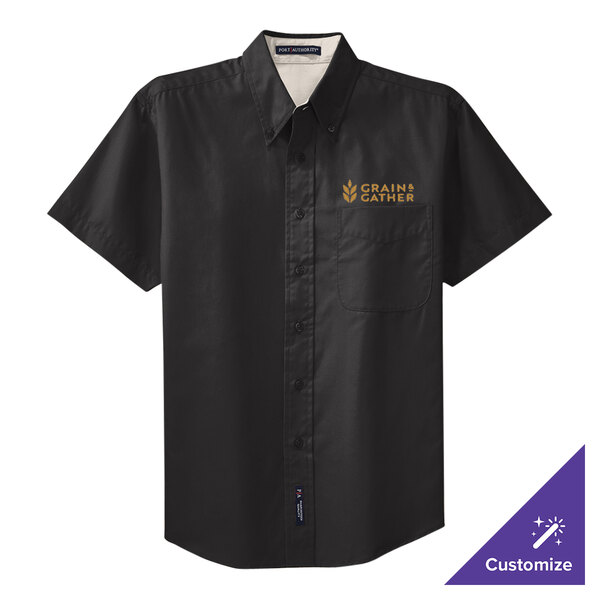 A black Port Authority short sleeve dress shirt with light stone accents and a logo embroidered in gold on the chest.
