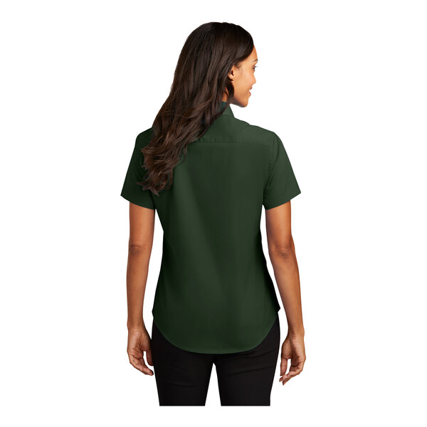 A woman wearing a Port Authority dark green short sleeve dress shirt.