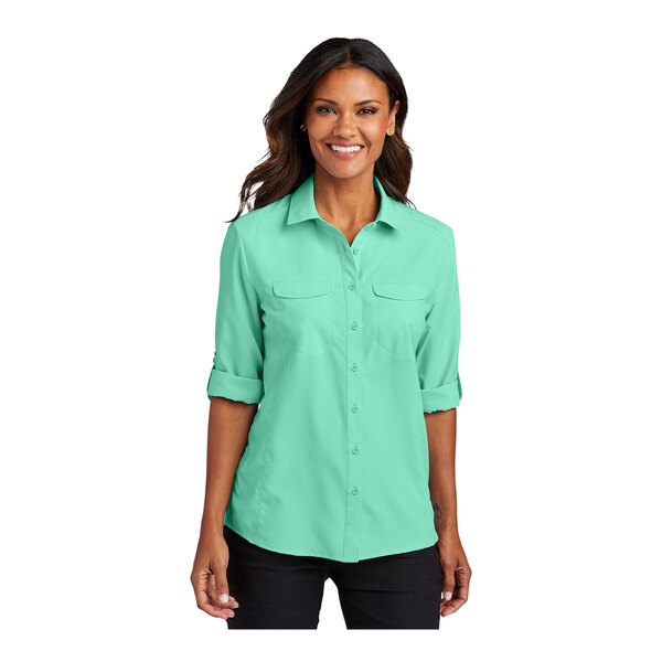 A woman wearing a bright seafoam green Port Authority short sleeve shirt.
