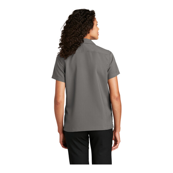 A woman wearing a graphite short sleeve Port Authority staff shirt.
