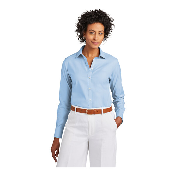 A woman wearing a Brooks Brothers Newport blue long sleeve dress shirt with white pants.