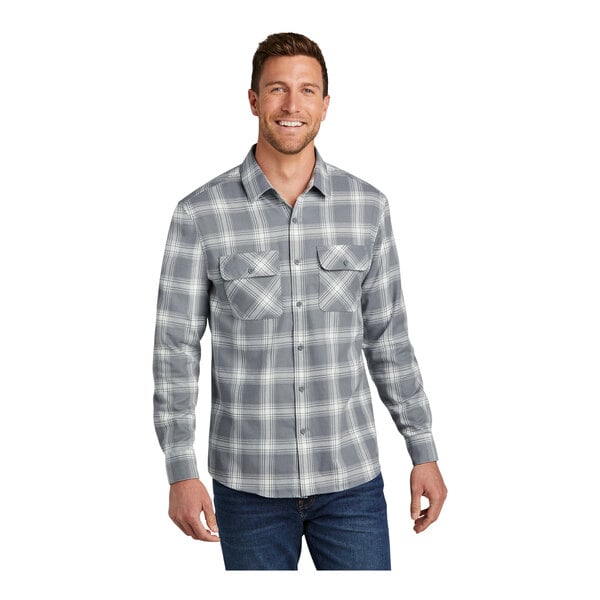 A man wearing a Port Authority gray and cream plaid flannel shirt.