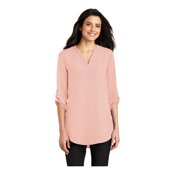 A woman wearing a rose quartz Port Authority short sleeve blouse with a v-neck.