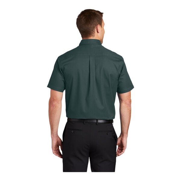 A man wearing a dark green and navy Port Authority dress shirt with short sleeves.