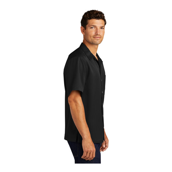 A close-up of a man wearing a black Port Authority short sleeve camp shirt.